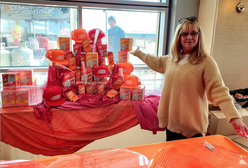 Dewey Business Partnership volunteer decorator Karen McMahon shows off assorted Dewey Crush canned cocktails and merchandise. SUBMITTED PHOTO